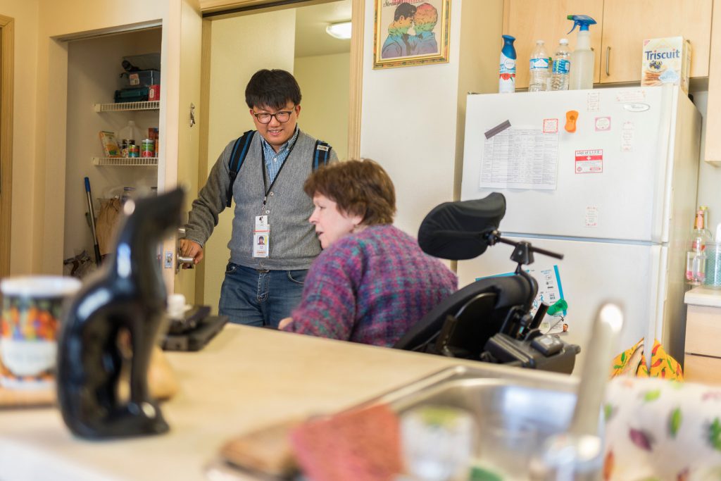 A young man stands in the door talking to an older woman in a wheel chair